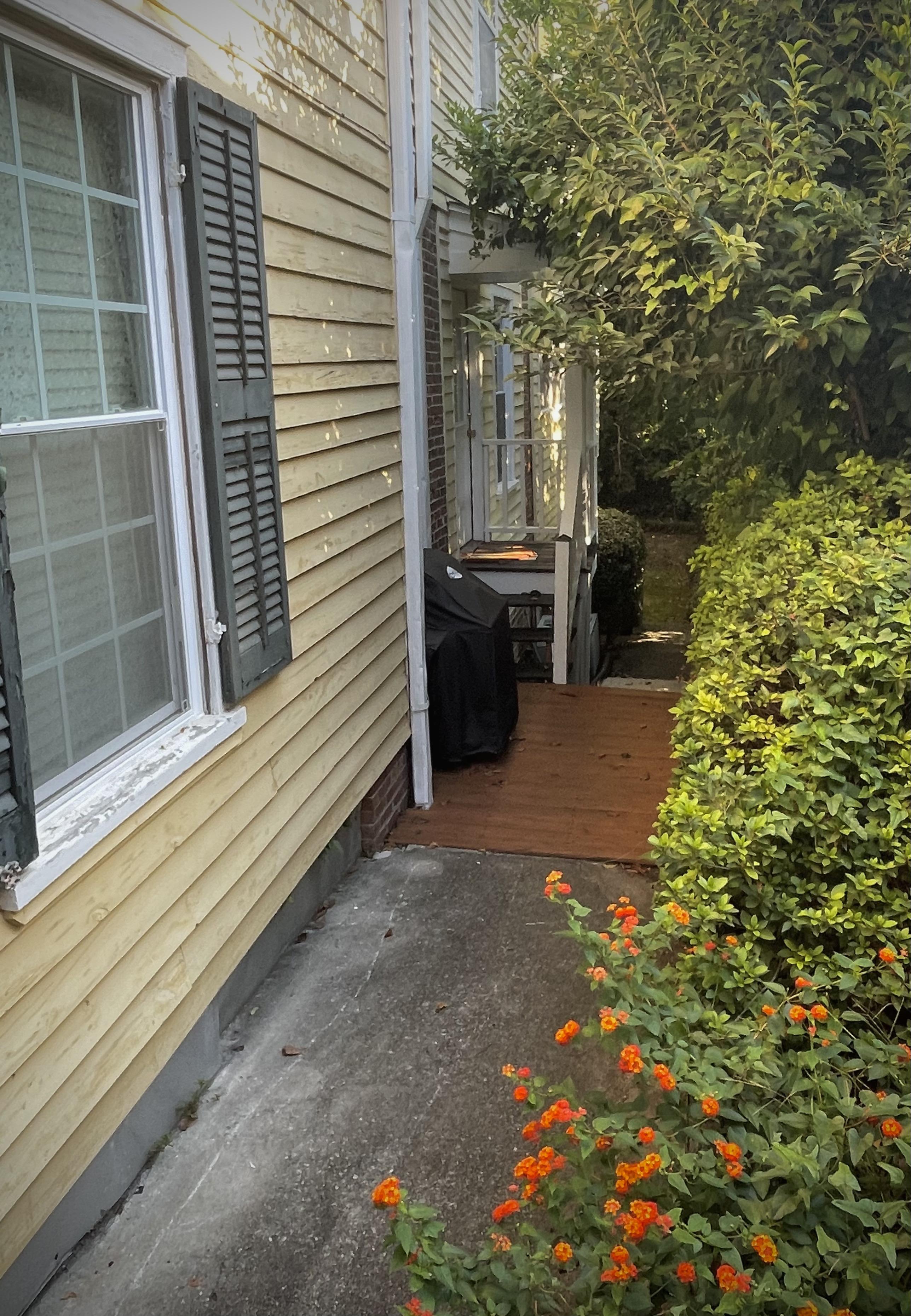 Walkway to small covered porch with covered grill at left for tenant use